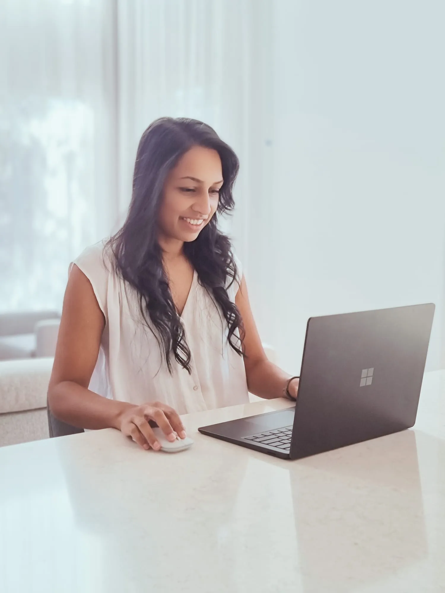 Nicole Jayawickreme working at a laptop at a kitchen bench, smiling